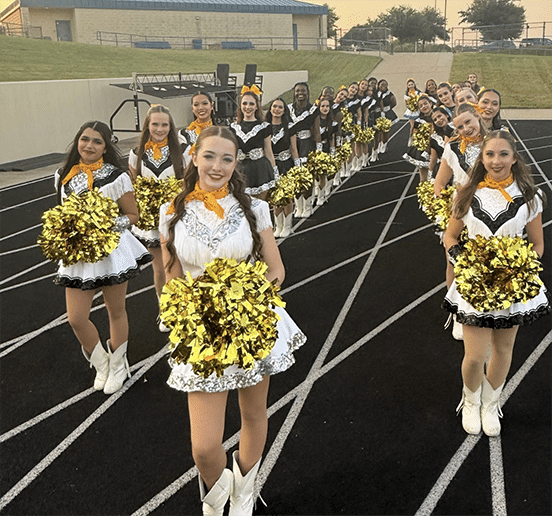 Rows of cheer team girls in cheerleading uniforms with gold pompoms