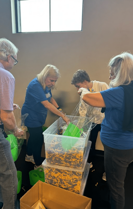 four people standing around a large plastic bin and filling backs with what is inside