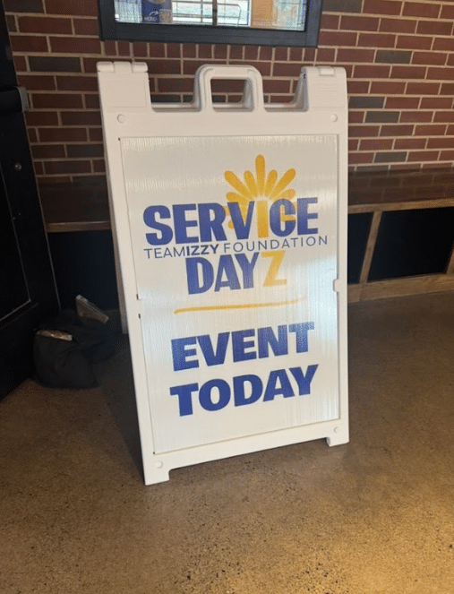 A folding ground sign announcing and event called Service Dayz