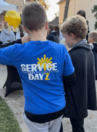 the back of a child in a blue shirt that says Service Dayz on it