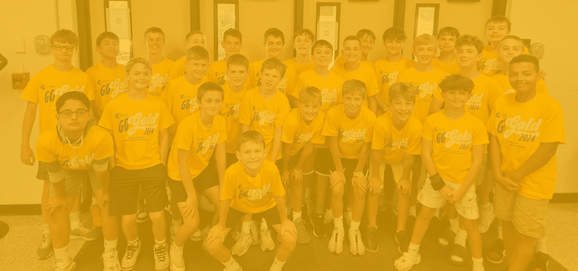 A photo of smiling kids all toegether wearing Go Gold t-shirts