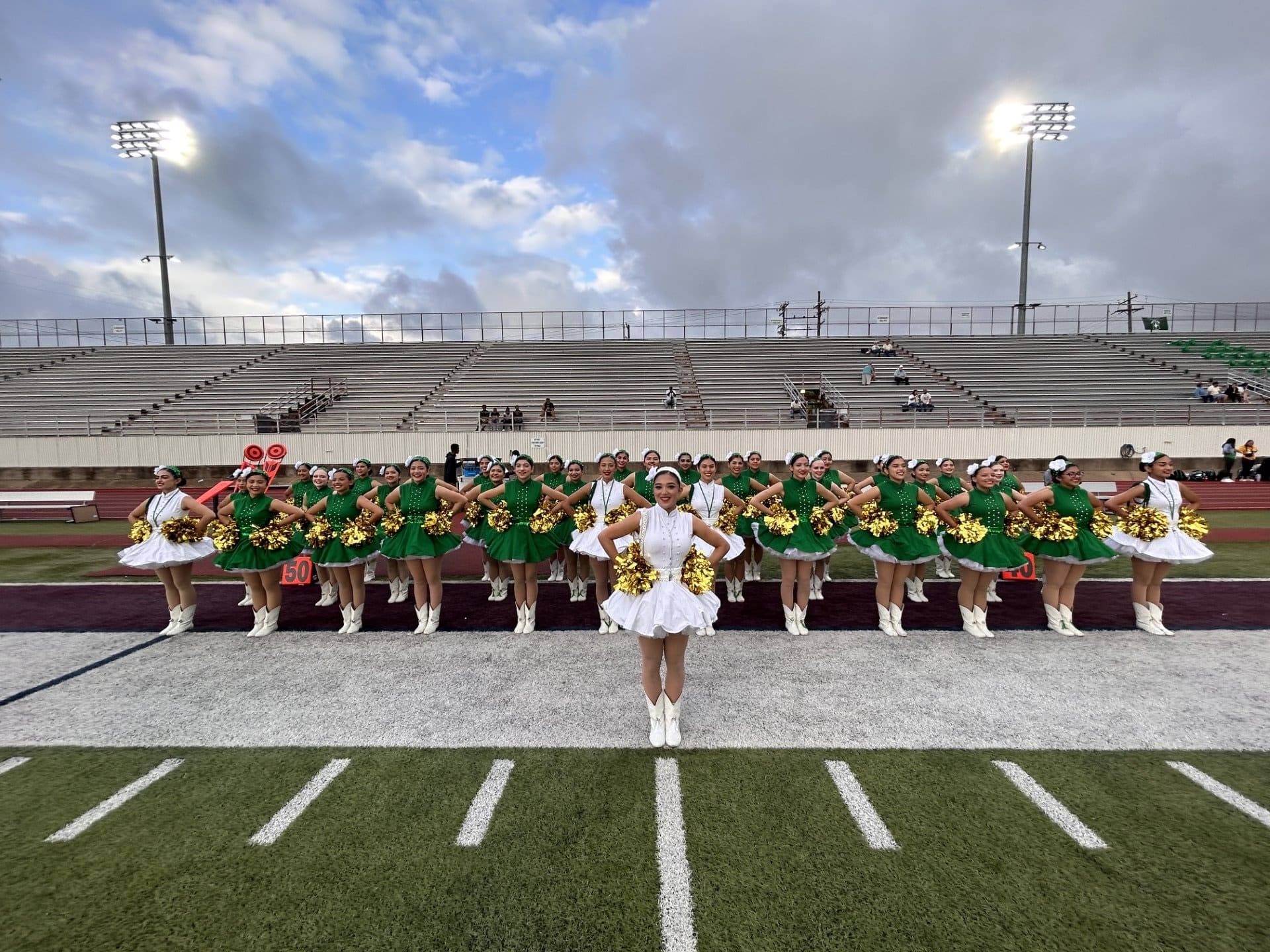 a big group of cheerleaders on a football field