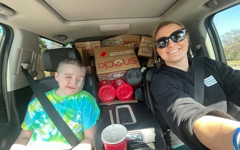 a car with a driver and child as passenger. the car is loaded with boxes in the back
