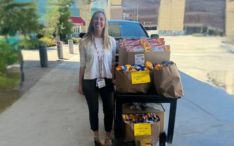a woman with a cart full of food in bags and goxes