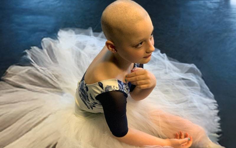 a child in a ballet outfit with no hair