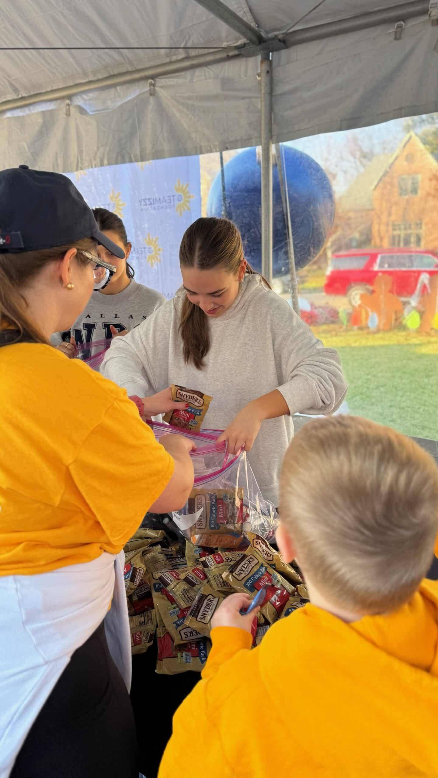 People under a tent. A girl is loading a plastic bag