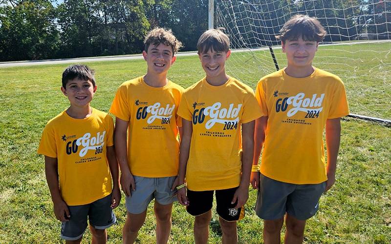 4 kids in gold shirts that say Go Gold on them