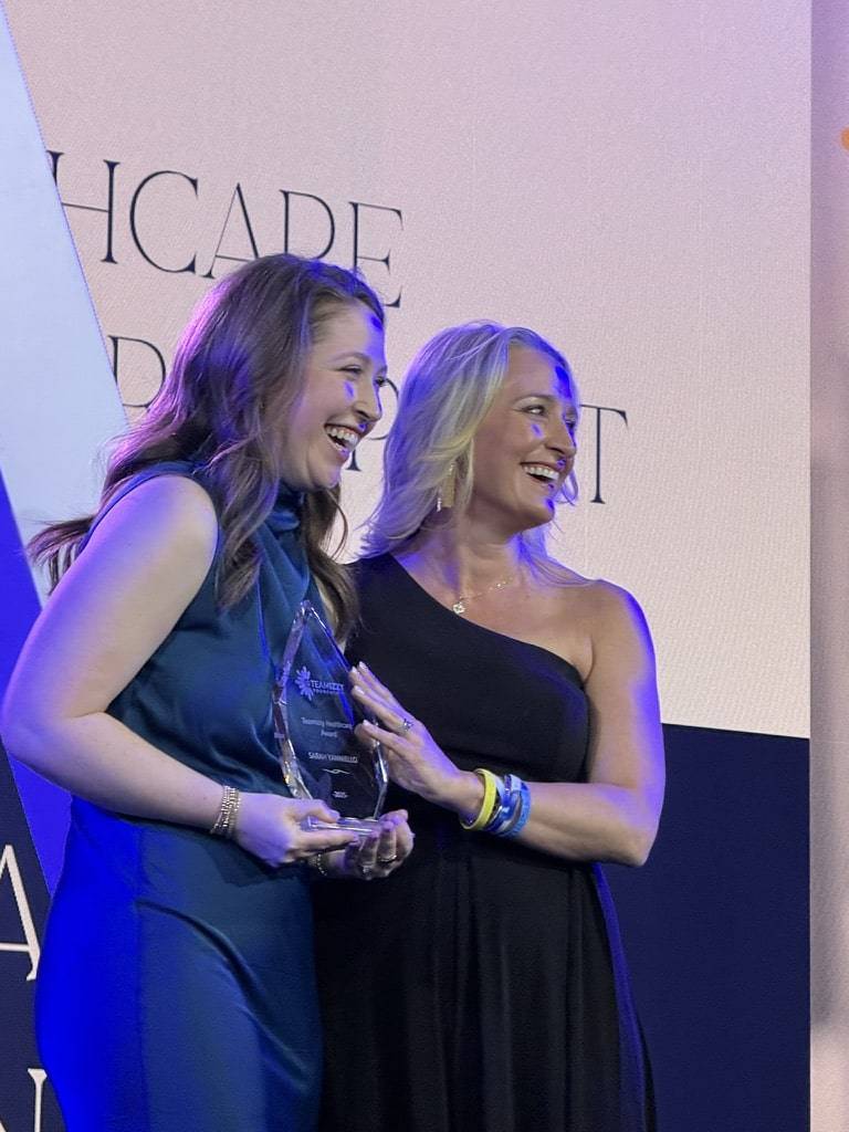 Two women standing up receiving an award