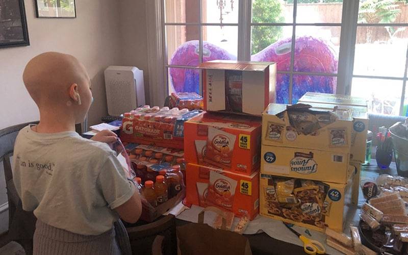 a child standing in front of a table full of packaged food