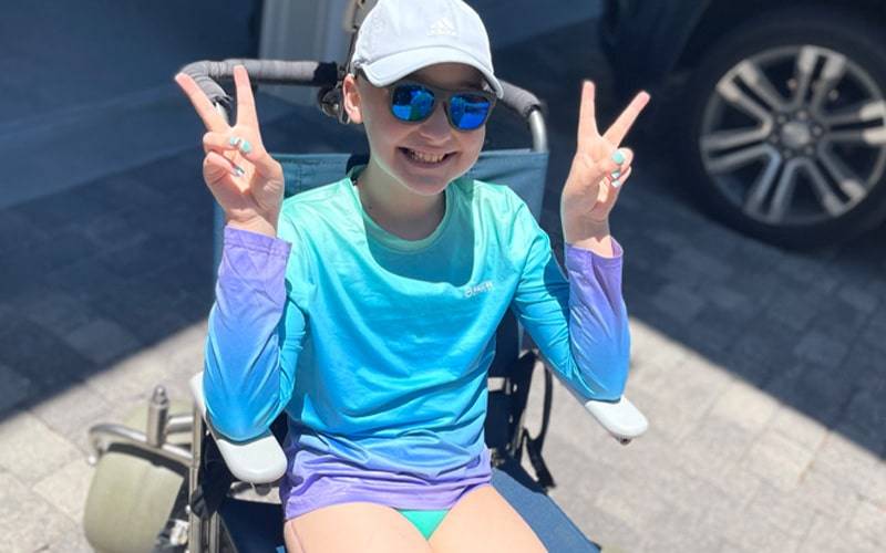A girl in a wheelchair makeing a peace sign